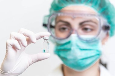 Coronavirus salgını için aşı şişesi tutan koruyucu eldivenli doktor ya da hemşire. İlaç ve uyuşturucu kavramı.
