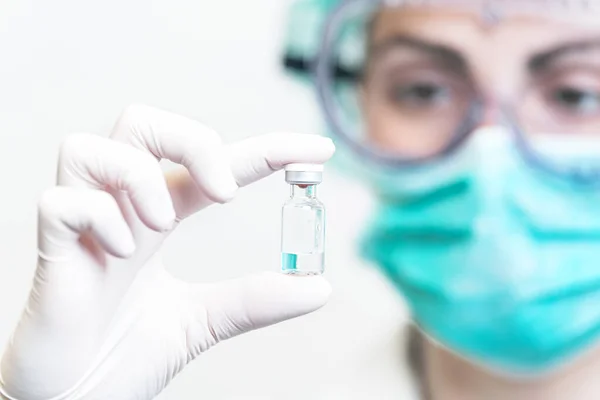 Medico o infermiere in guanti protettivi con flaconcino di vaccino per la pandemia da focolaio di Coronavirus. Medicina e concetto di droga . — Foto Stock