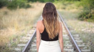 Hareket konsepti ve geleceğe bakmak. Arkadan bir kadın demiryolunda dikiliyor ve uzaklığa bakıyor..