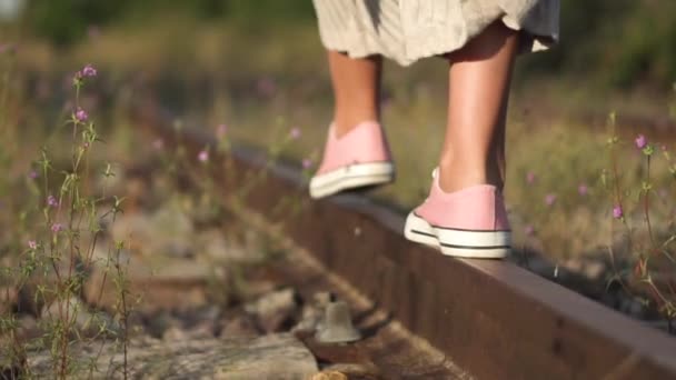 Fille marchant le long du chemin de fer. Plan romantique de suivi au ralenti de jeunes filles pieds gros plan marchant le long du rail de chemin de fer en été . — Video