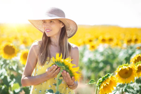 Piękna kobieta z kapeluszem na polu słonecznika w lecie. — Zdjęcie stockowe