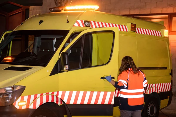 Night scene of an unrecognizable Paramedic, Ambulance woman driver at work, ready to assist an emergency. — Stock Photo, Image