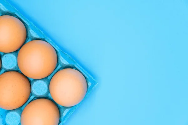 Сырые коричневые куриные яйца на синем фоне . — стоковое фото