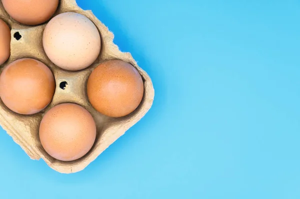 Сырые коричневые куриные яйца на синем фоне . — стоковое фото