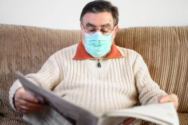 Coronavirus salgını sırasında gazete okuyan yaşlı bir adam karantina altında..