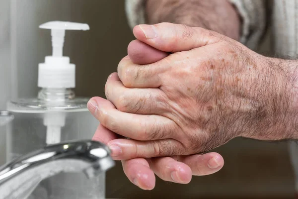 Пожилые люди, употребляющие алкогольный антисептический гель, предотвращают инфекцию, вспышку ковид-19. Старший мужчина моет руки дезинфицирующим средством, чтобы избежать заражения коронавирусом . — стоковое фото
