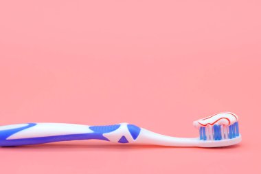 Pembe arka planda kırmızı diş macunu kıvrımlı beyaz diş fırçası. Diş ve sağlık hizmetleri kavramı.