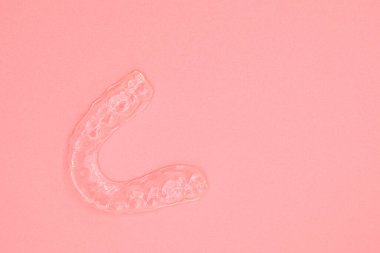 Plastik diş izi. Ortodontik silikon eğitmeni. Pembe arka planda diş düzeltmesi için mobil ortodonti aygıtı.
