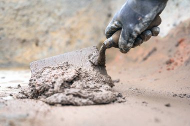 İnşaat işçisi eli havan topu karıştırmak için mala kullanıyor.