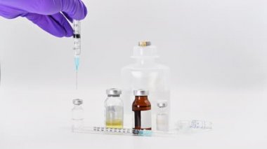 İlaç bilimcisi elinde şırıngayla şişeye sıvı enjekte ediyor. Coronavirus aşısı araştırması. Beyaz arkaplanda ilaç şişeleri.