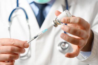 Doktor aşı için şırıngayı hazırlar..