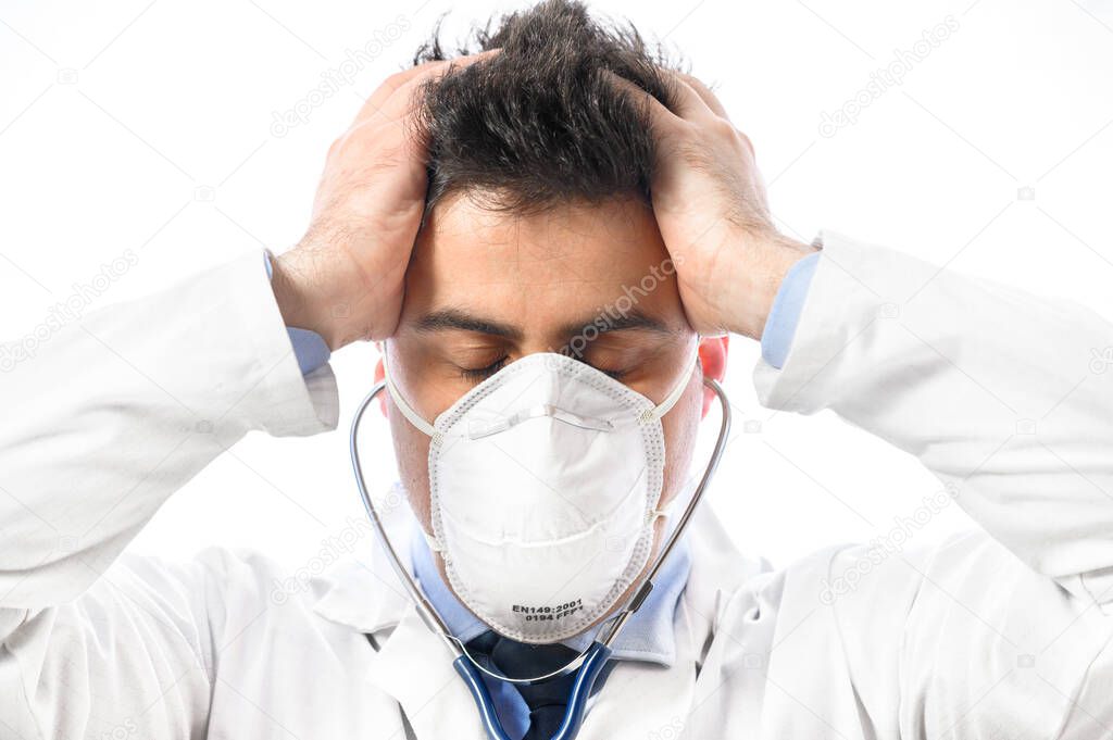 Anxious and nervous doctor. Close up portrait, of a doctor in protective face mask with worried expression, whose put his hands on the head. Pandemic coronavirus outbreak.