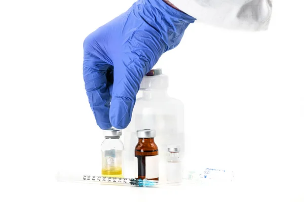 Pharmaceutical picking up a vaccine vial on the table. Coronavirus vaccine research. Medicine vials in white background. — Stock Photo, Image