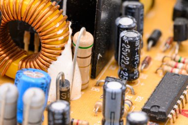 Elektronik parçaları olan eski model baskılı devre kartı. Ön planda elektronik bobin var. Sığ DOF ile yakın plan.
