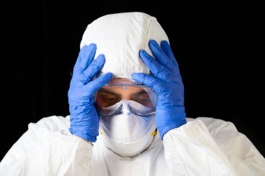COVID-19. Korunma ekipmanlarıyla yorgun düşmüş Doktor, Coronavirus 'un enfekte olduğu vakalar ve ölüm bilançolarının artmasından endişeleniyor. Sağlık çalışanlarının duygusal stresi.