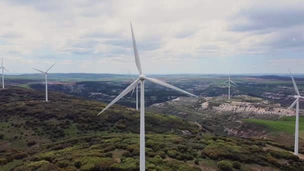 美しい曇りの空にクリーンエネルギー生産のための風車農場の空中ビュー。風力発電タービンは、持続可能な開発のためのクリーンな再生可能エネルギーを生み出す. — ストック動画