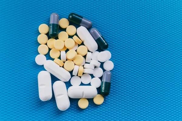 La montaña de pastillas. Depresión, beriberi. Medicamento de color sobre un fondo azul — Foto de Stock