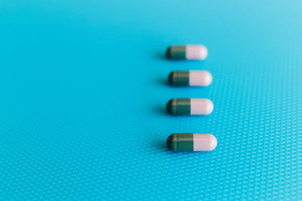 薬のカプセルの形で薬のカプセルの形で灰色の青の背景に緑のカプセル — ストック写真