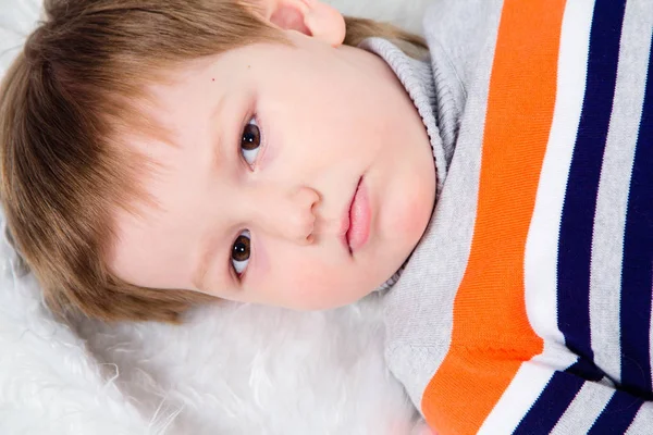 Serious view of the child, the boy lies on his back, gaze of children — Stock Photo, Image