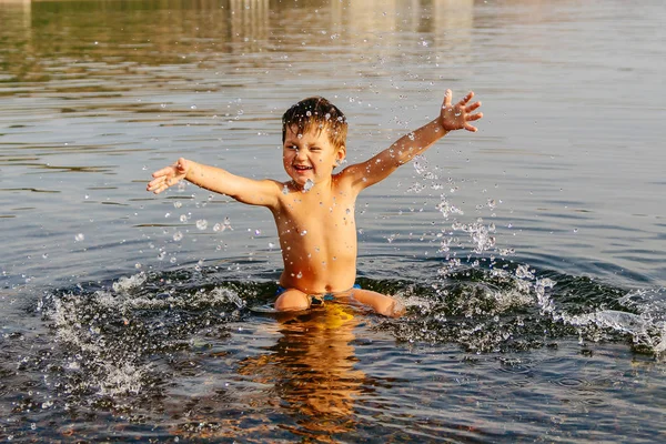 小男孩溅水。阳光明媚的夏日, 在温暖的湖水中游泳 — 图库照片