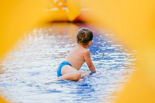 Мальчик купается в детском бассейне. Мальчик играет в надувном бассейне. через отверстие, рамка . — стоковое фото