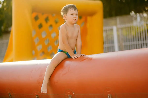 Ten chlapec sedí na trampolíně. tři rok staré dítě sedí na bazén nafukovací fotbalové — Stock fotografie