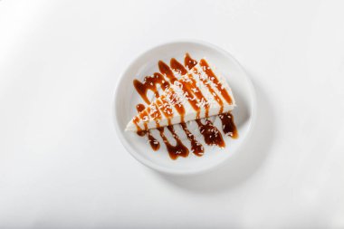 güzel beyaz lor peynirli kek ile karamel ve Hindistan cevizi gevreği beyaz plaka üzerinde