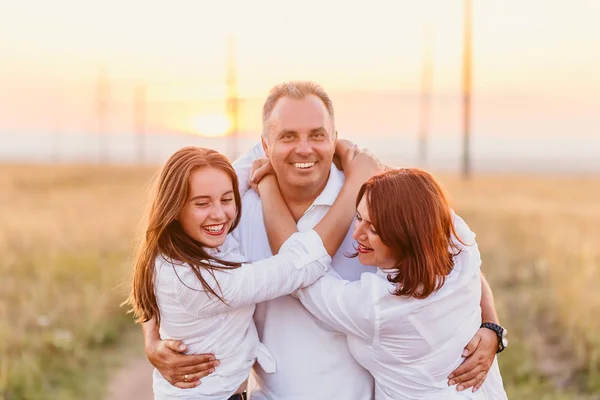 Glada roliga familj i vita skjortor i solnedgången — Stockfoto