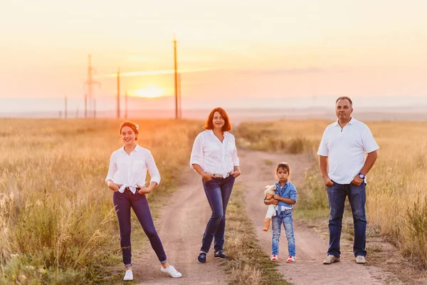 Lycklig familj i fältet vid solnedgången — Stockfoto