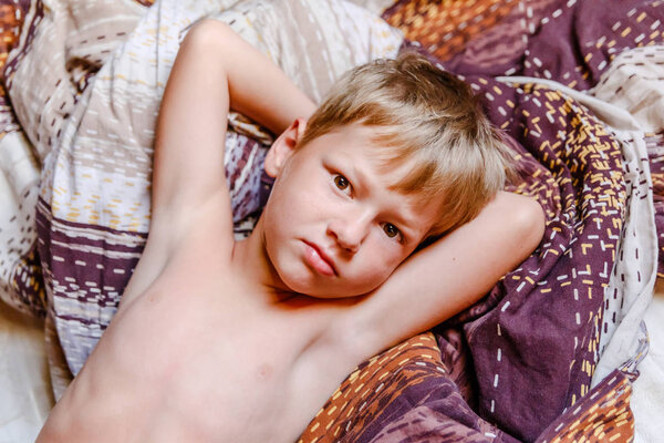 the fair boy woke up and lies in bed