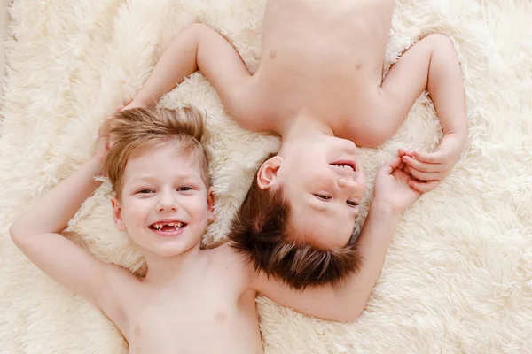 Two cheerful boys lie on the bed and laugh — Stock Photo, Image