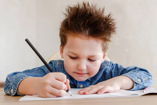 Маленький хлопчик малює кольоровим олівцем на столі — стокове фото
