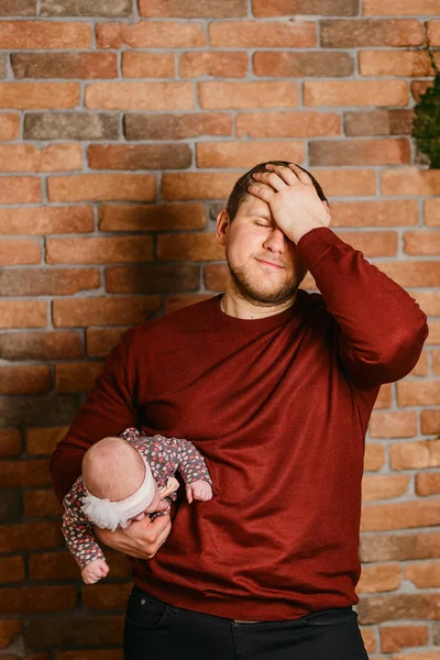 Ung pappa med dotter under armen mot en tegelvägg — Stockfoto