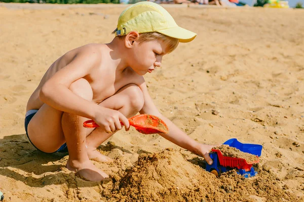 Мальчик играет с машиной в песке — стоковое фото