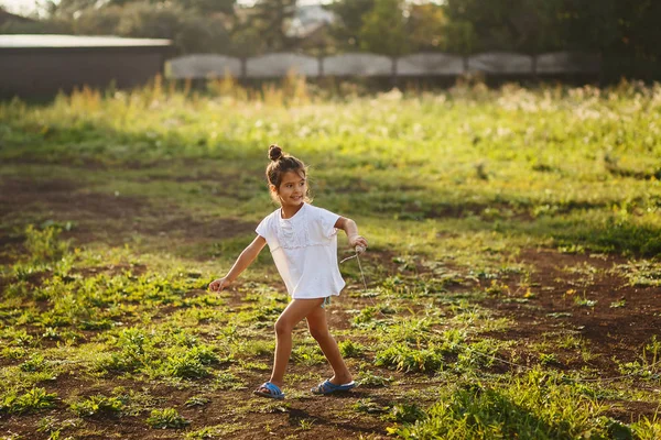 Morena niña de cinco años corriendo sobre la hierba en el verano —  Fotos de Stock