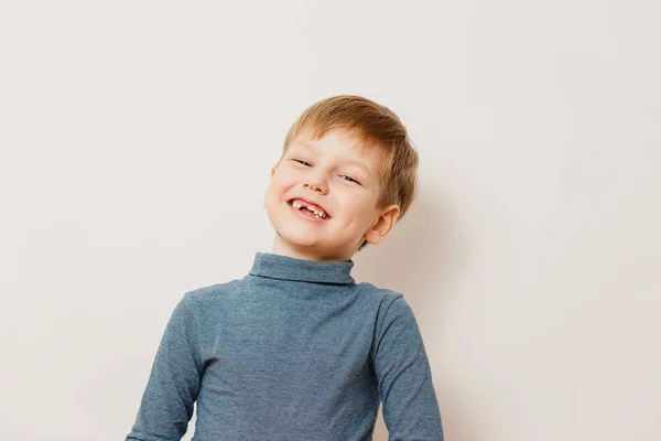 Веселый беззубый мальчик шестилетний в полосатой водолазке на белом фоне — стоковое фото