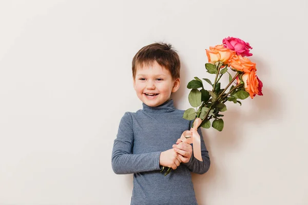 Красивый веселый мальчик с букетом роз на белом фоне — стоковое фото