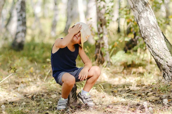 Yaz aylarında bir güdük ormanda oturan şapkalı küçük çocuk
