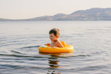 şişme bir daire göl kenarında küçük bir çocuk yüzüyor