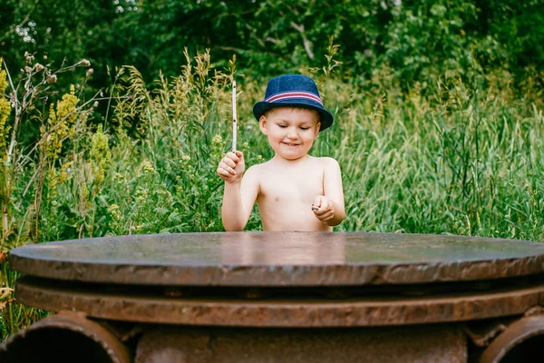 Pojken i hatten spelar i den gröna skogen — Stockfoto