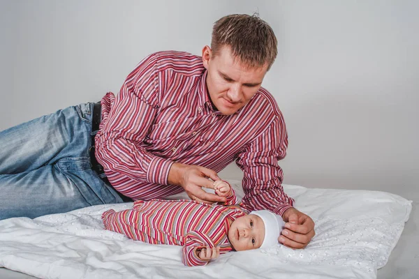 Молодой человек держит ручку новорожденного сына на белом фоне — стоковое фото