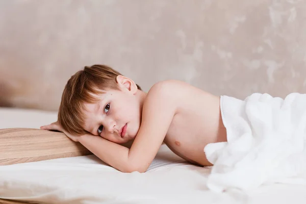 Sad boy six years old lying on the bed — Stock Photo, Image