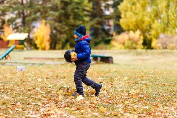 Маленький мальчик бегает с мячом осенью — стоковое фото