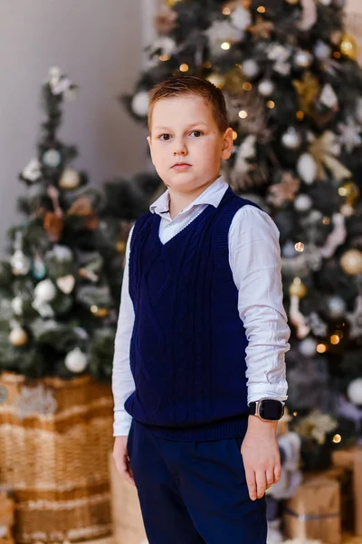 8-летний мальчик рубашка и жилет на фоне елки — стоковое фото