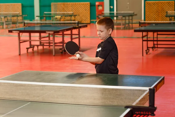 serving the ball in table tennis, children and sports. a boy looks at a table tennis ball