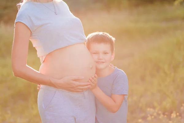 Bebé Sonriente Abraza Gran Vientre Una Madre Embarazada Cerca Del —  Fotos de Stock
