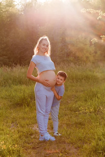 Niño Abraza Una Mujer Embarazada Verano Parque Una Luz Contorneada —  Fotos de Stock