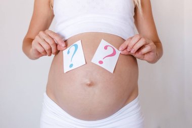 Hamile bir kadın karnında sorularla tabelalar taşır. Erkek ya da kız