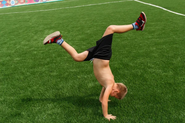 Çocuk stadyumda kollarında yürüyor. Çocuklar ve spor.
