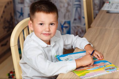 Çocuk evde renkli kalemlerle boyama yapıyor.